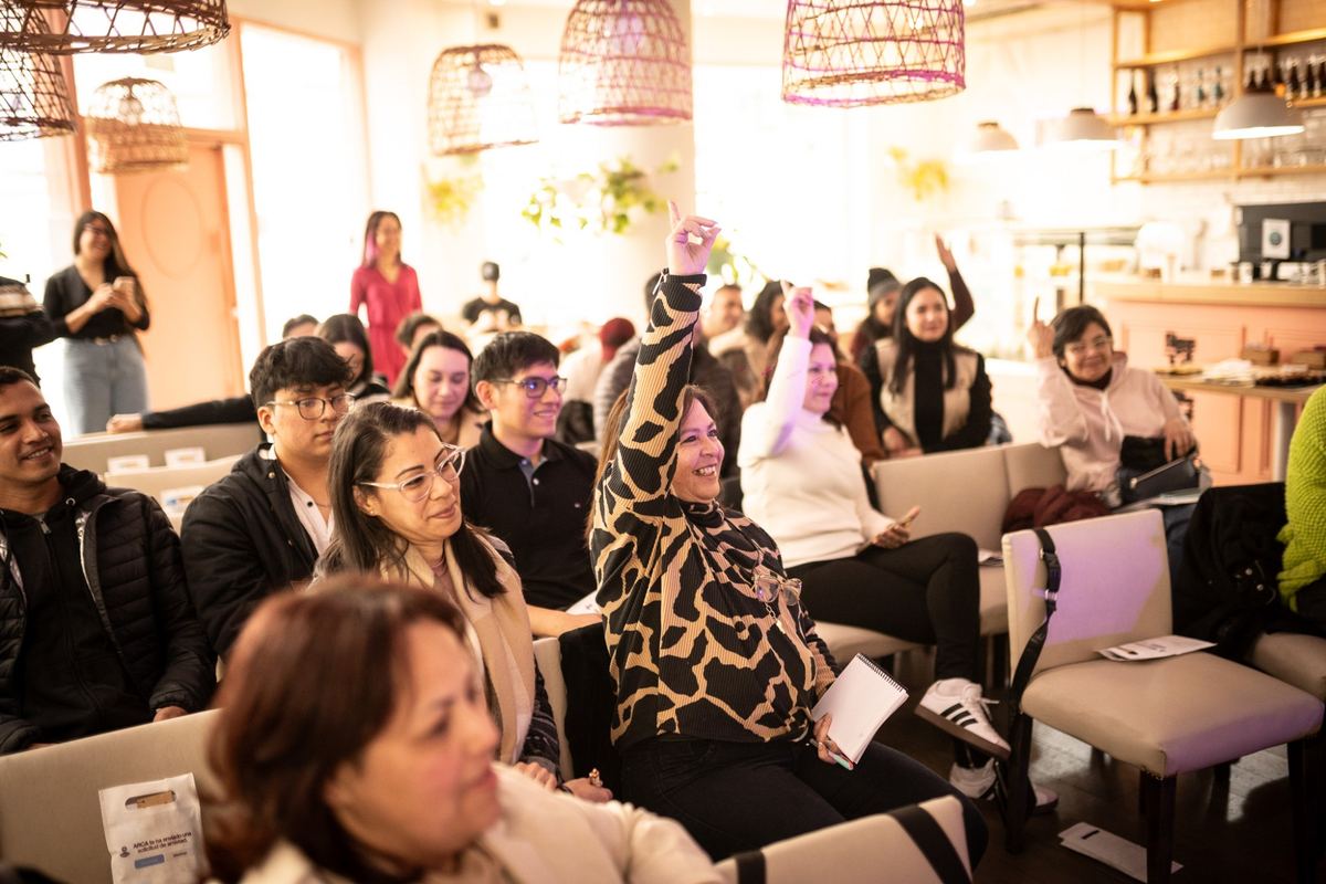 Asistentes de la primera edición de la MonoTRIBU Experience levantando la mano durante una charla, sentados en el salón de Marlon.